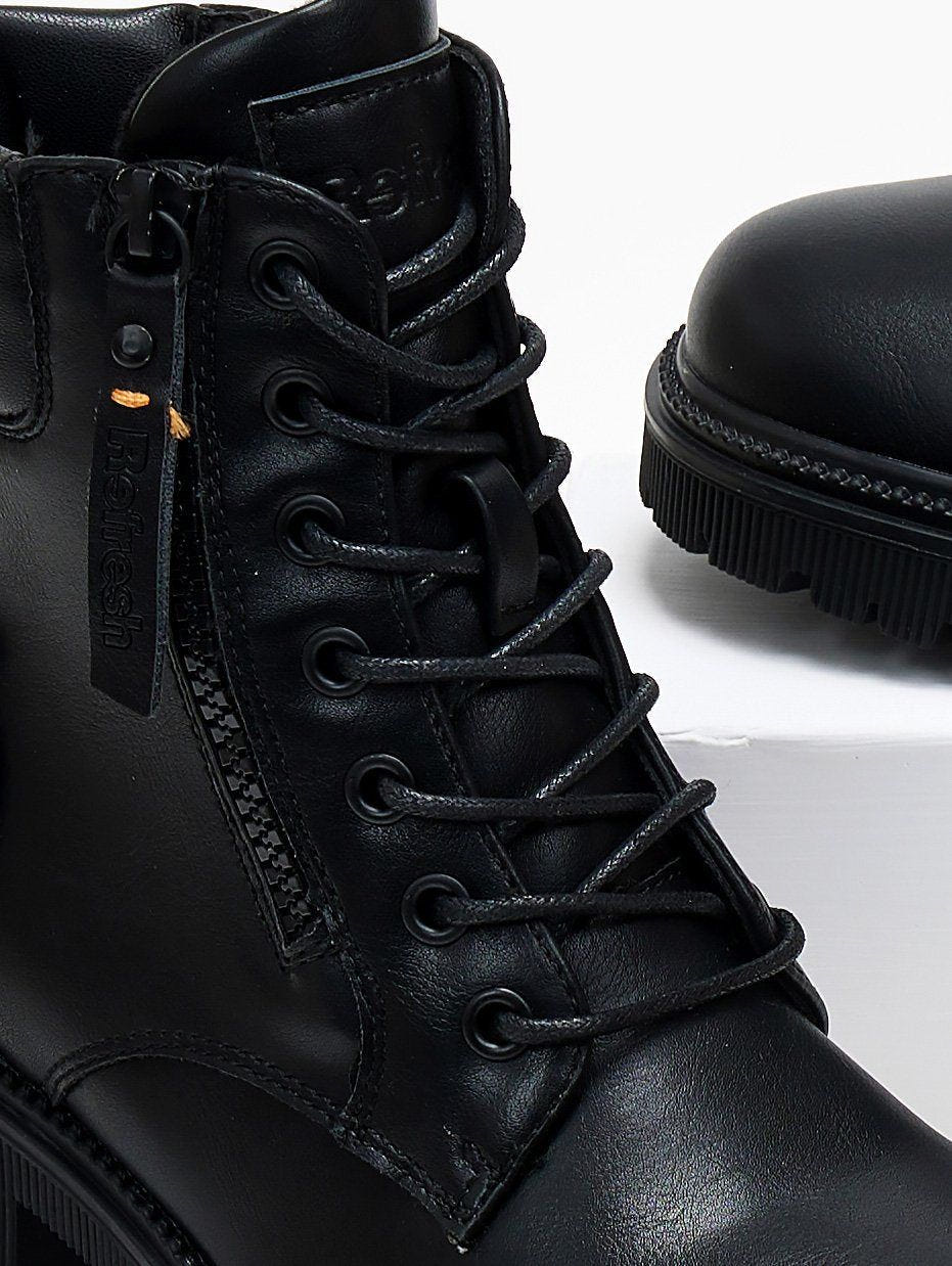 Close-up of black leather lace-up boot with zip detail and chunky sole, side view