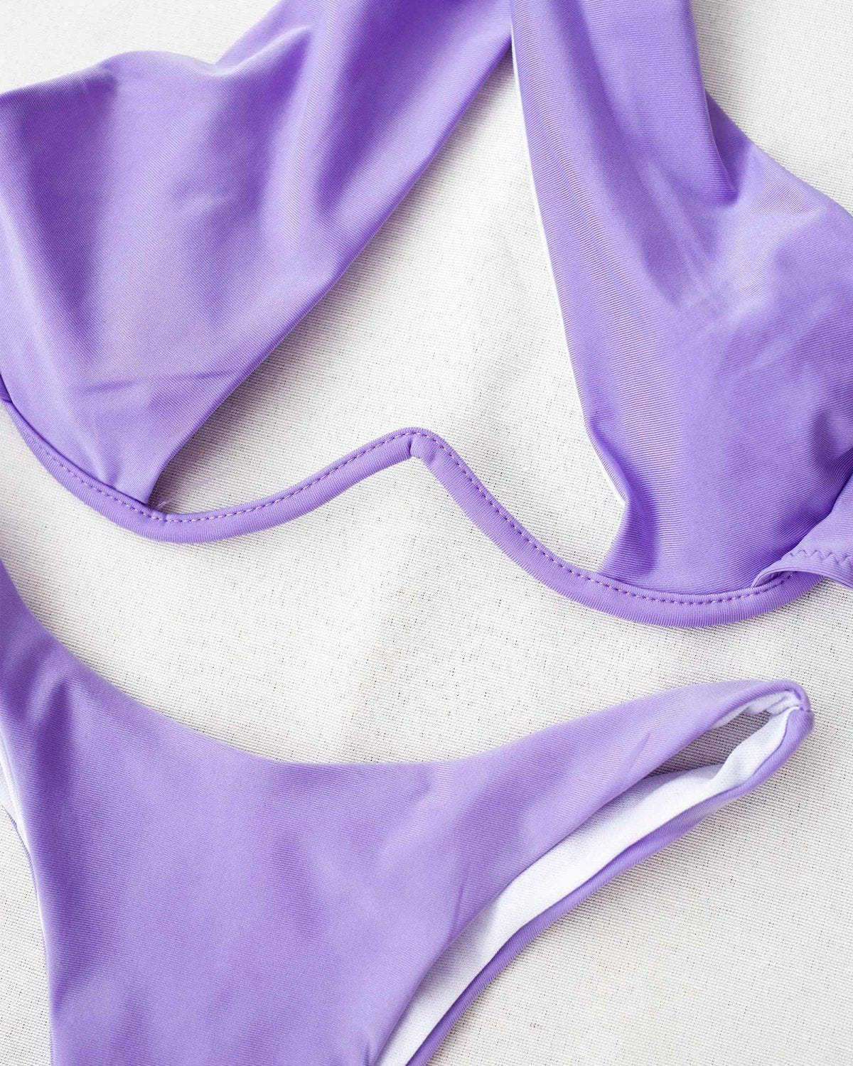 Close-up of lilac bikini top with cutout detail and lilac bikini bottom, laid flat on white