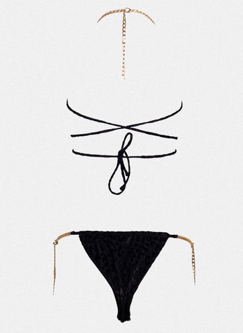 Black string bikini top with wrap straps and gold chain detail, matching black bikini bottom laid flat on white background