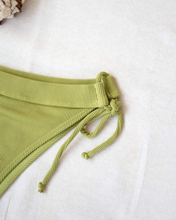 Close-up of lime green ribbed side-tie bikini bottom with tie detail, laid flat on white background