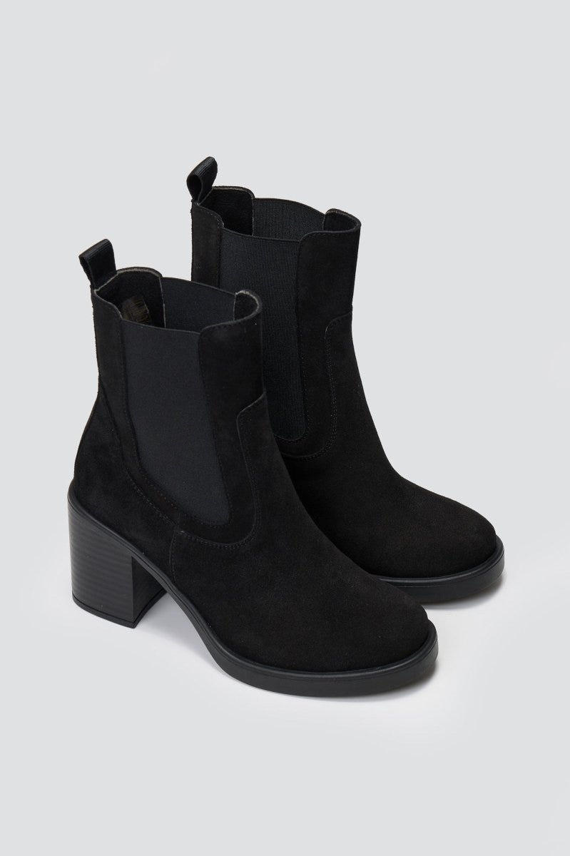 Black suede Chelsea ankle boots with block heel and elastic side panels, standing on grey backdrop