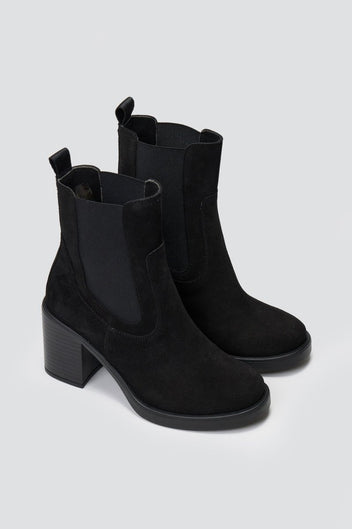 Black suede Chelsea ankle boots with block heel and elastic side panels, standing on grey backdrop