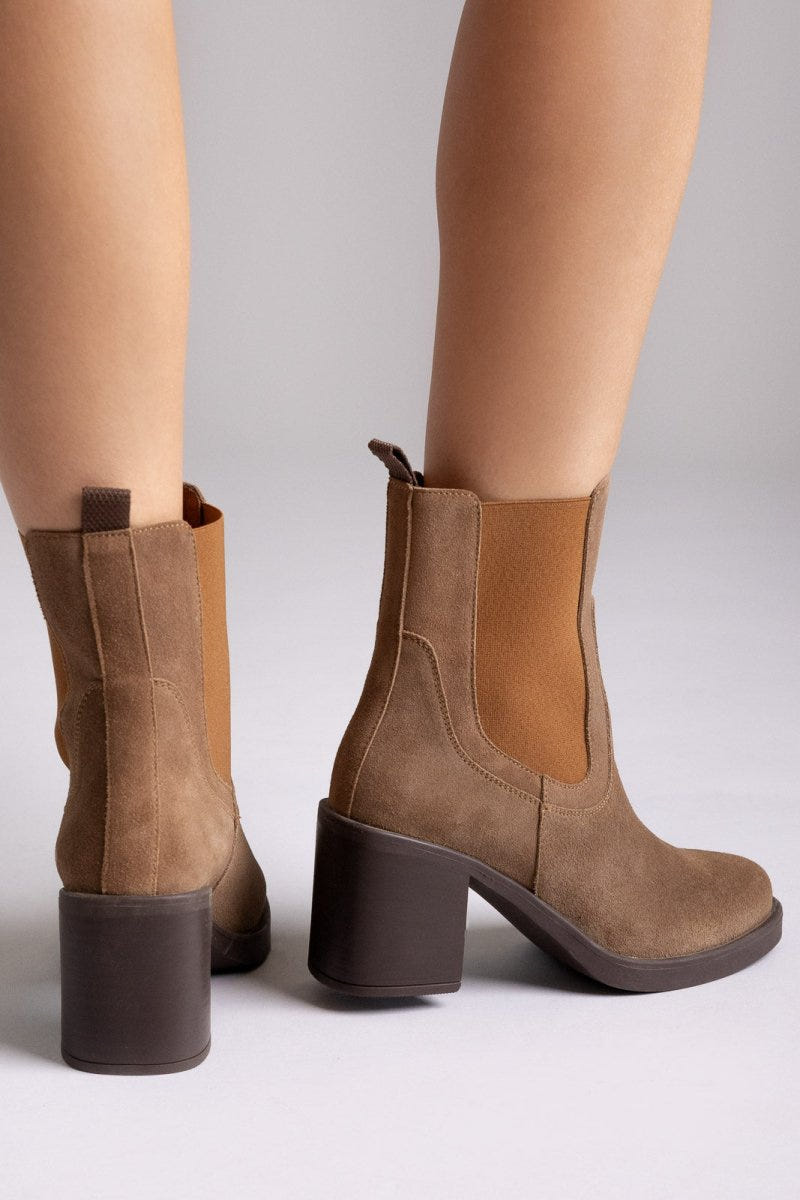 Model legs wearing tan suede Chelsea ankle boots with block heel and elastic side panels, close-up
