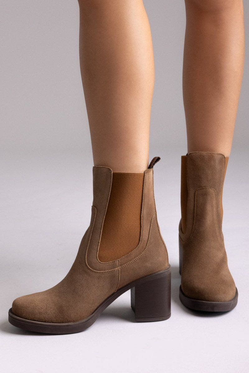 Model legs wearing tan suede Chelsea ankle boots with block heel and elastic side panels, front view