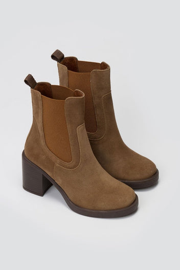 Tan suede Chelsea ankle boots with block heel and elastic side panels, standing on light grey backdrop