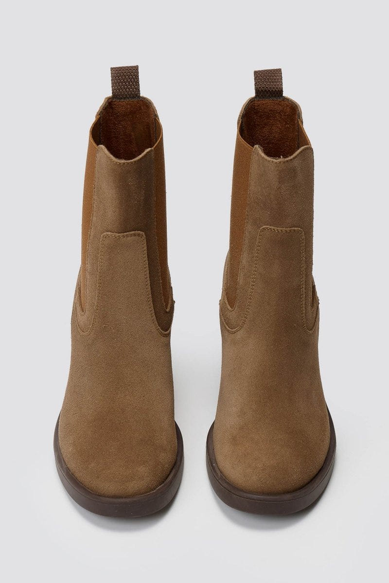 Tan suede Chelsea ankle boots with block heel and elastic side panels, front view on grey backdrop