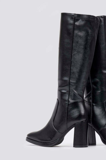 Black knee-high boot with a stacked block heel and pointed toe, side view on a light grey backdrop with a smooth leather finish