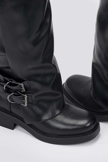 Close-up of black leather boot with a buckle strap and round toe, detail on a light grey background