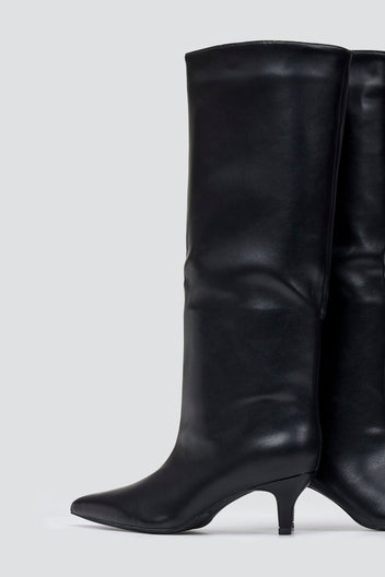 Black leather knee-high pointed toe boot with slouchy shaft and kitten heel, angled side view on a light grey background
