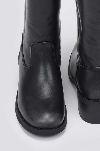 Close-up of black leather boot shaft and rounded toe with chunky sole on a light grey background