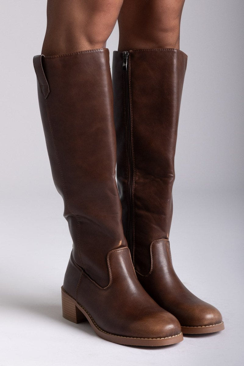 Pair of brown leather knee-high boots with round toes and tan block heels, front view on a light grey background