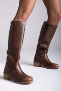 Model legs in brown leather knee-high boots with round toes and tan block heels, angled view on a light grey background