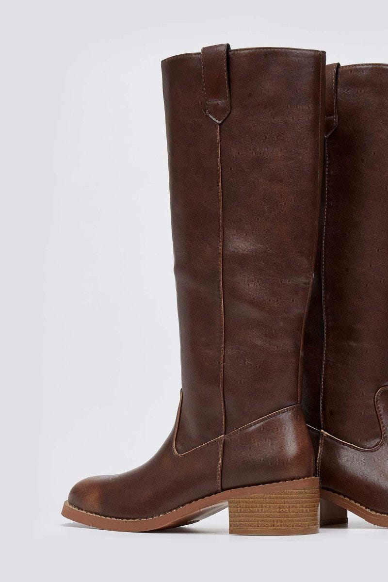 Brown leather knee-high boot with round toe and tan block heel, front view on a light grey background