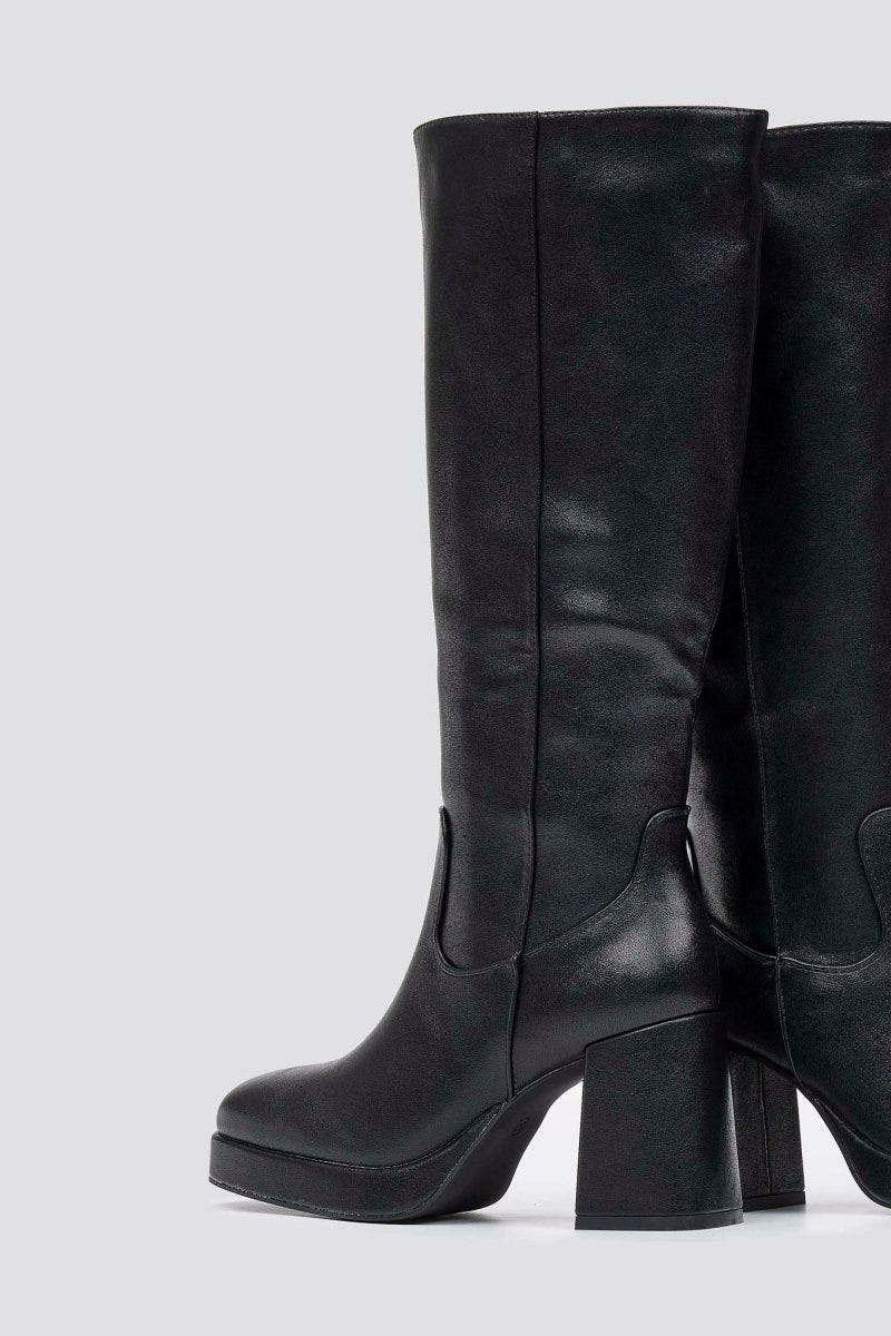 Black knee-high platform block heel boot with side zip, side view on light grey background