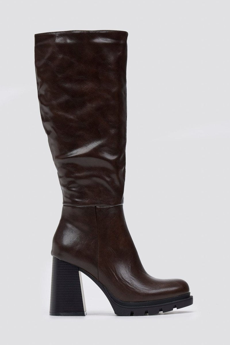 Dark brown knee-high platform block heel boot with slouched shaft and lug sole, front view on light grey background