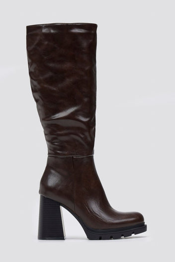 Dark brown knee-high platform block heel boot with slouched shaft and lug sole, front view on light grey background