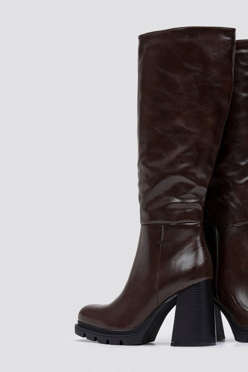 Dark brown knee-high platform block heel boot with slouched shaft and lug sole, side view on light grey background