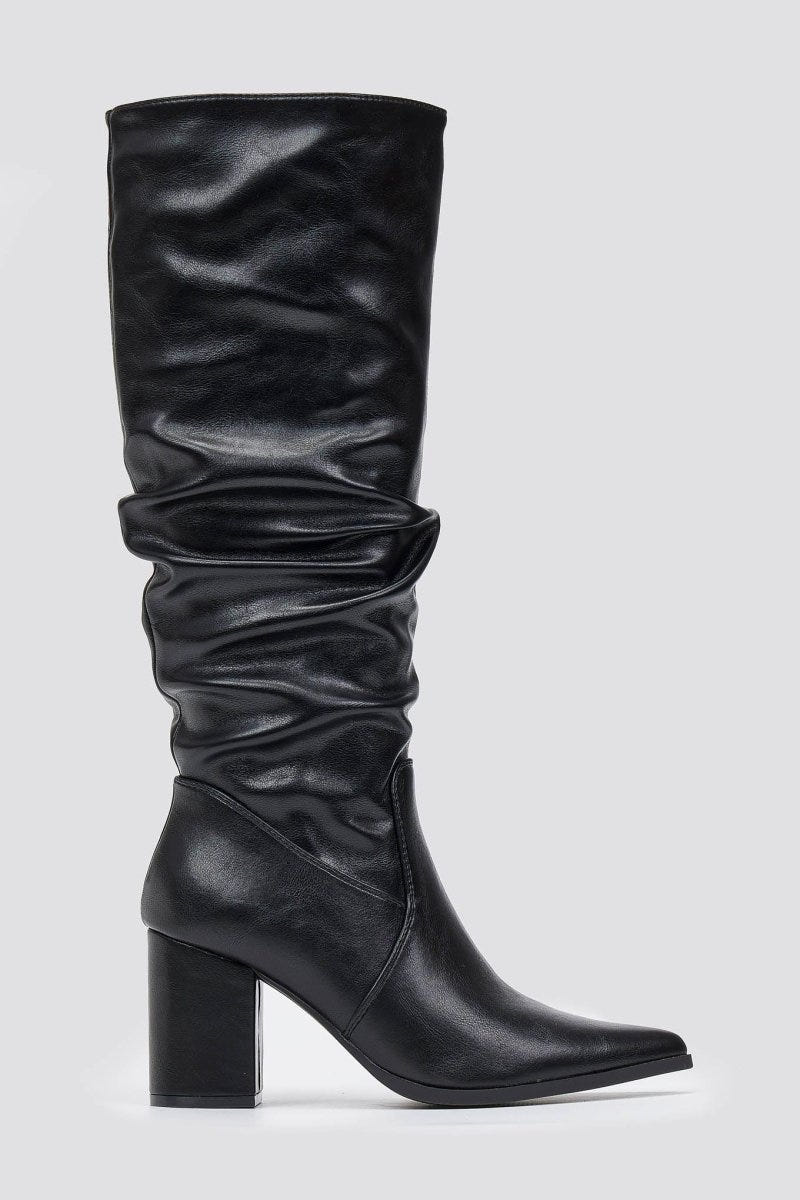 Black knee-high pointed toe block heel boot with slouched shaft and ruched leg, front view on light grey background