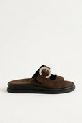 Dark brown suede slide sandal with decorative rhinestone buckle and dark chunky sole, angled view on a light grey background