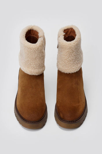 Pair of tan suede shearling-cuff ankle boots with lug soles, overhead view on a light grey background