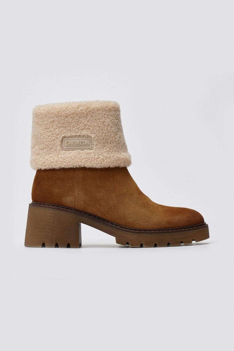 Tan suede shearling-cuff ankle boot with block heel and lug sole, angled view on a light grey background