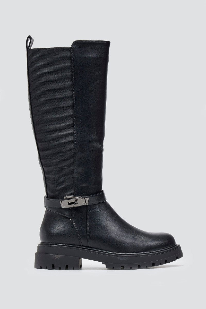 Black knee-high lug sole boot with textured shaft and buckle strap, side view on a light grey background