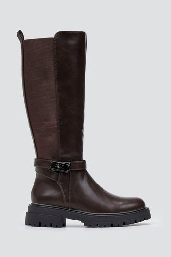 Dark brown knee-high lug sole boot with textured shaft and buckle strap, side view on a light grey background