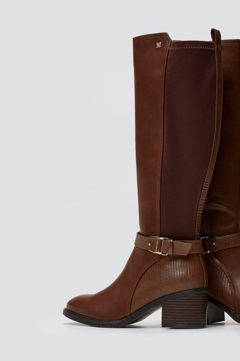 Tan brown leather knee-high block heel boot with buckle strap and stretch panel, side view on a light grey background