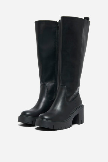 Pair of black leather knee-high boots with chunky block heels and side zip, angled view on a light grey background