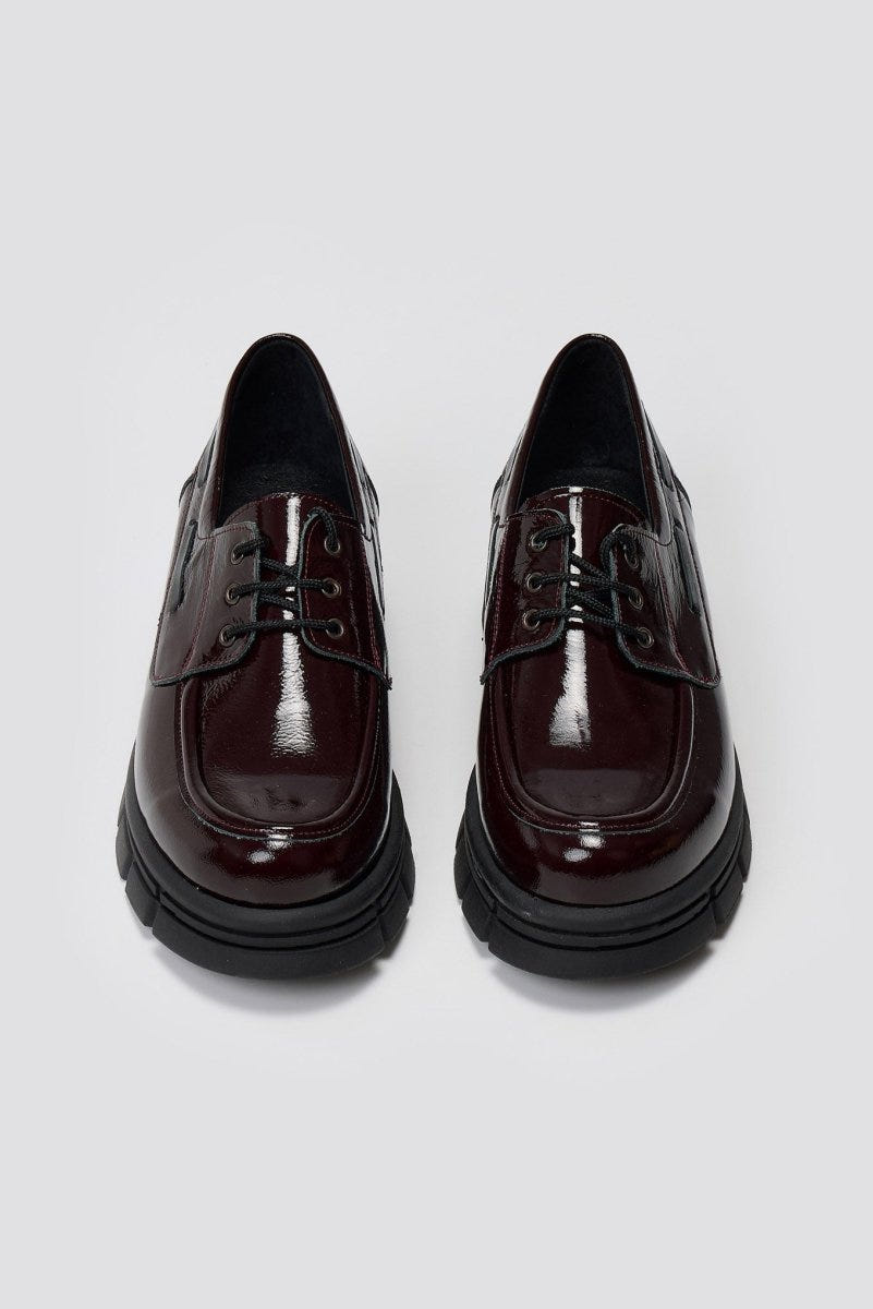 Pair of burgundy patent leather chunky sole lace up shoes, laid flat from above on light grey background
