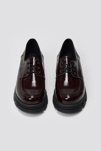 Pair of burgundy patent leather chunky sole lace up shoes, laid flat from above on light grey background