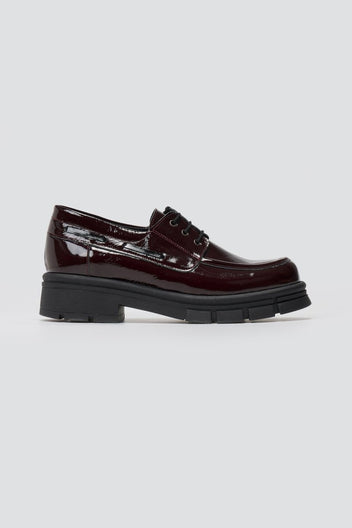 Burgundy patent leather chunky sole lace up shoe, side view on light grey background