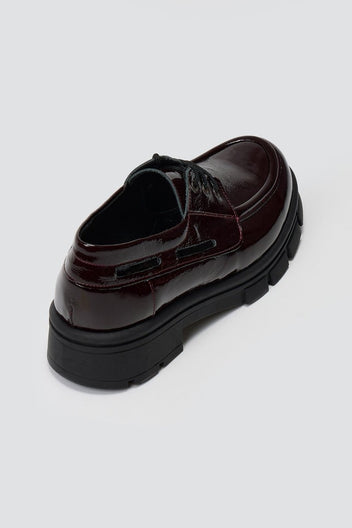 Burgundy patent leather chunky sole lace up shoe, angled top view on light grey background