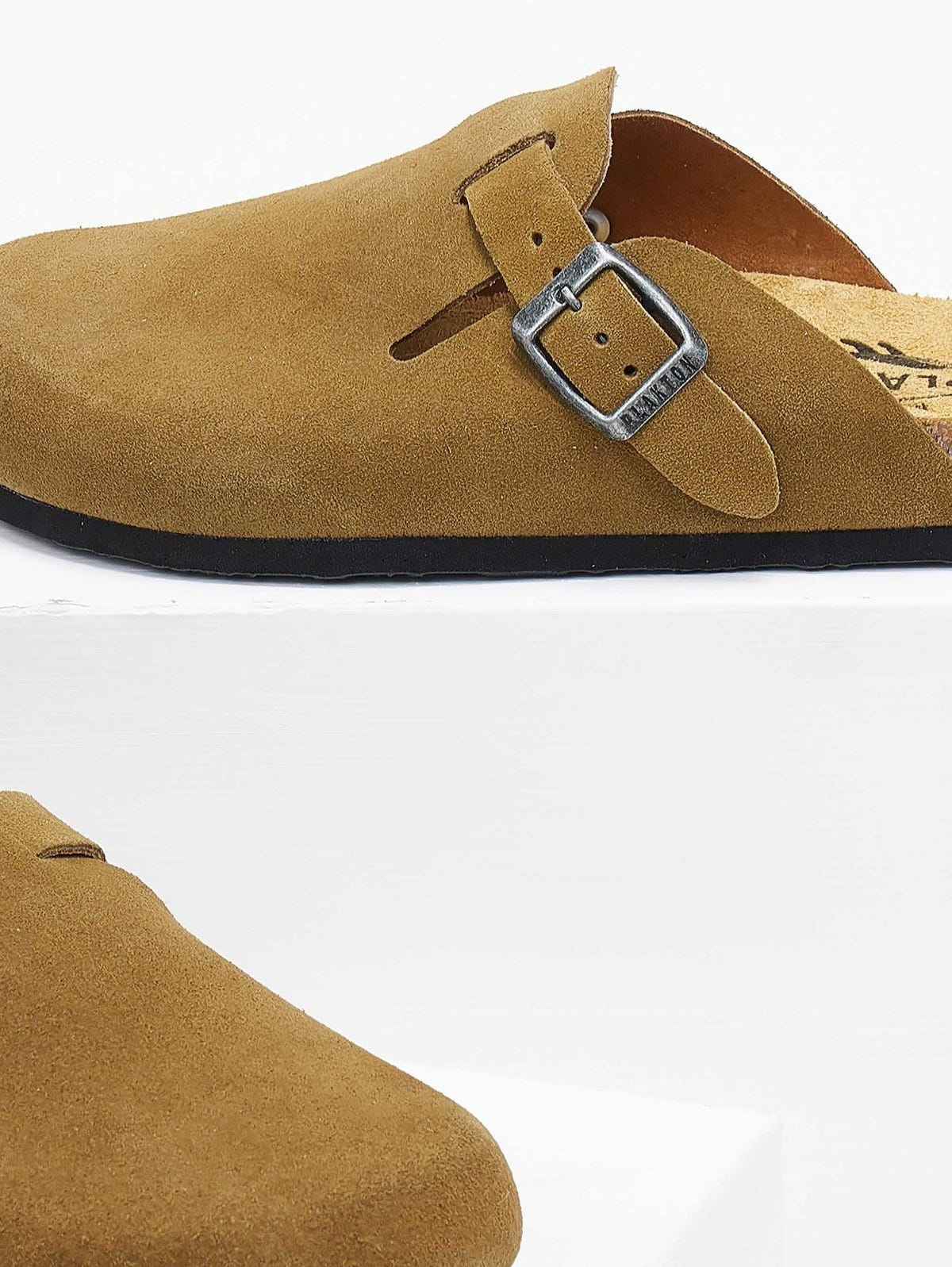 Close-up of olive suede clog buckle strap with silver tone buckle and dark rubber sole edge
