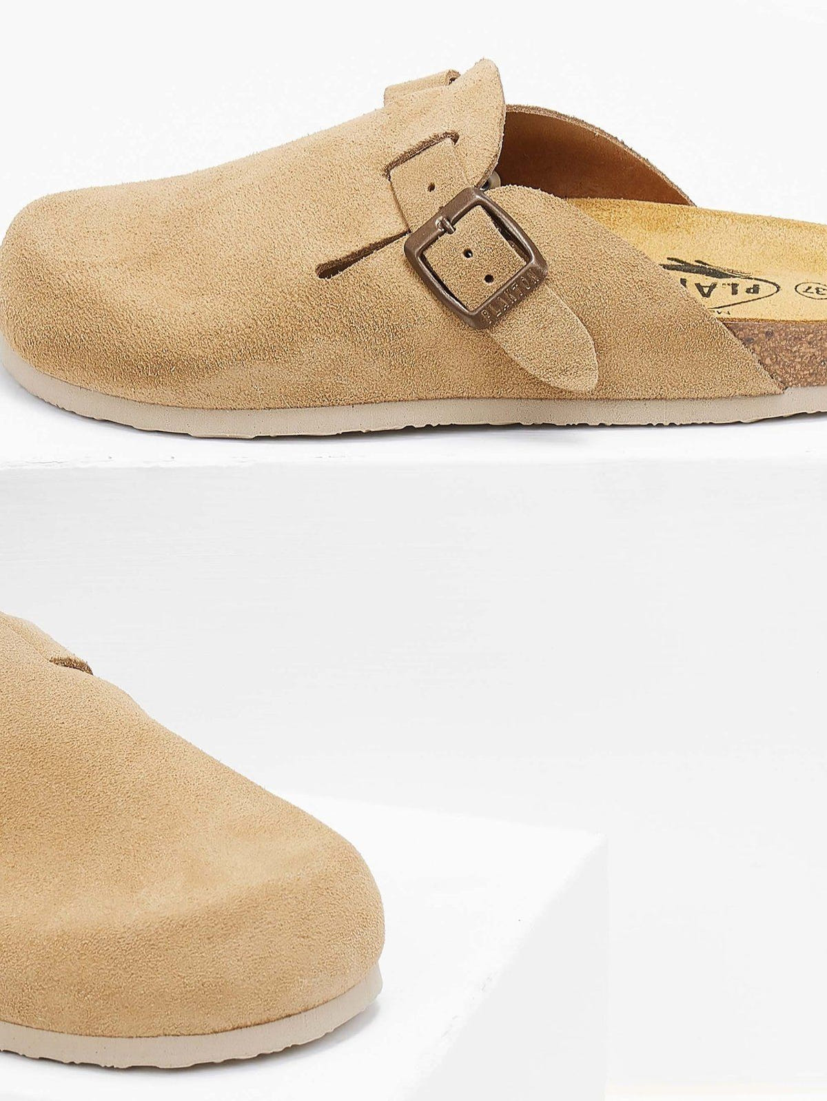 Close-up of beige suede clog toe area and buckle strap resting on a white block with soft shadow