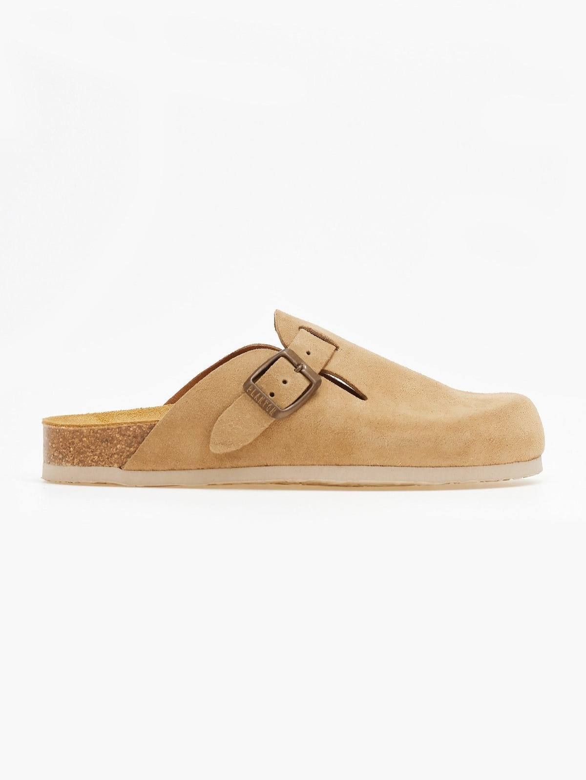 Side view of single beige suede clog with buckle strap and cork footbed on a white surface