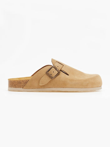 Side view of single beige suede clog with buckle strap and cork footbed on a white surface