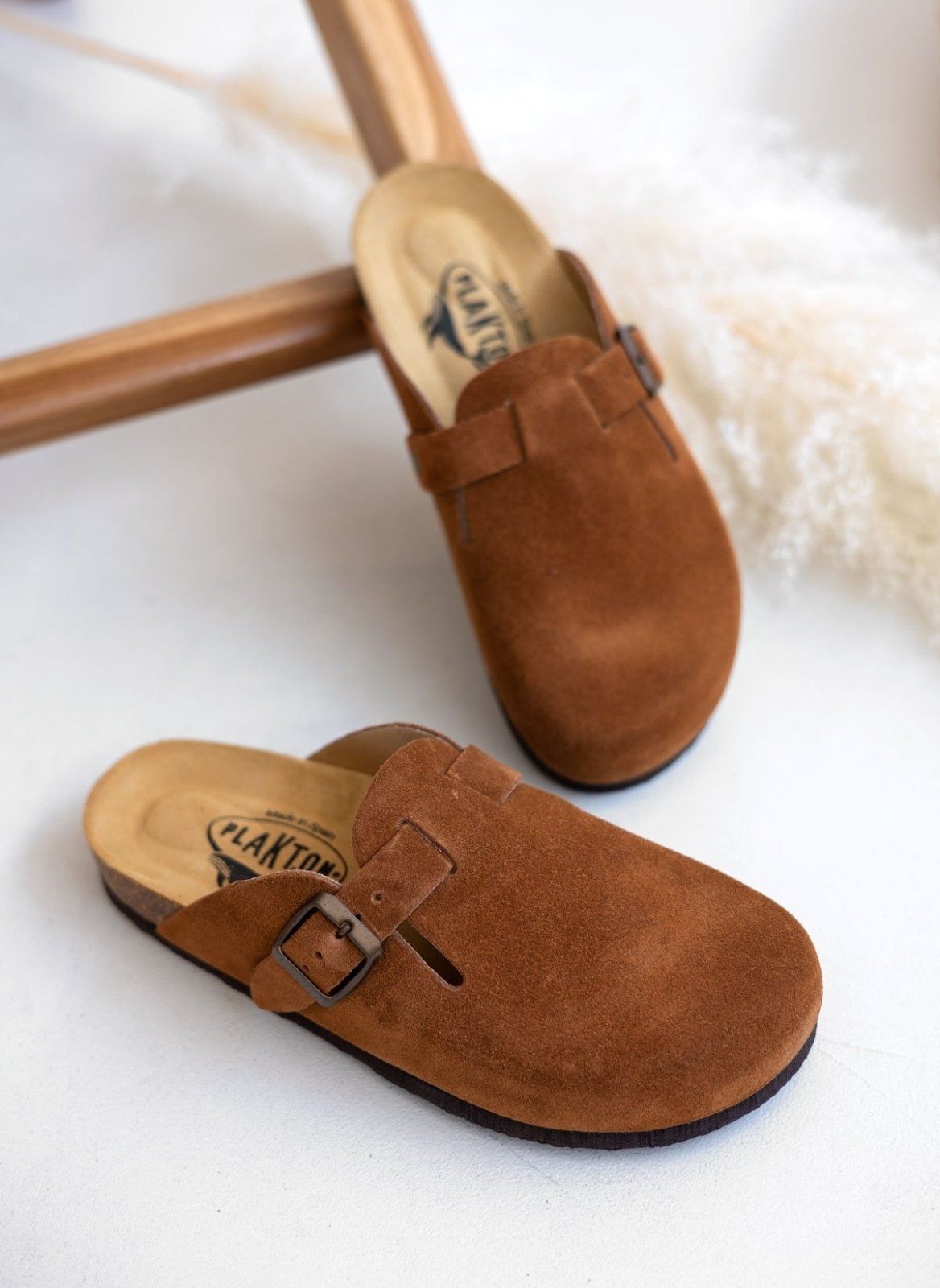 Brown suede clog with buckle strap and cork footbed, overhead angled view on a light background