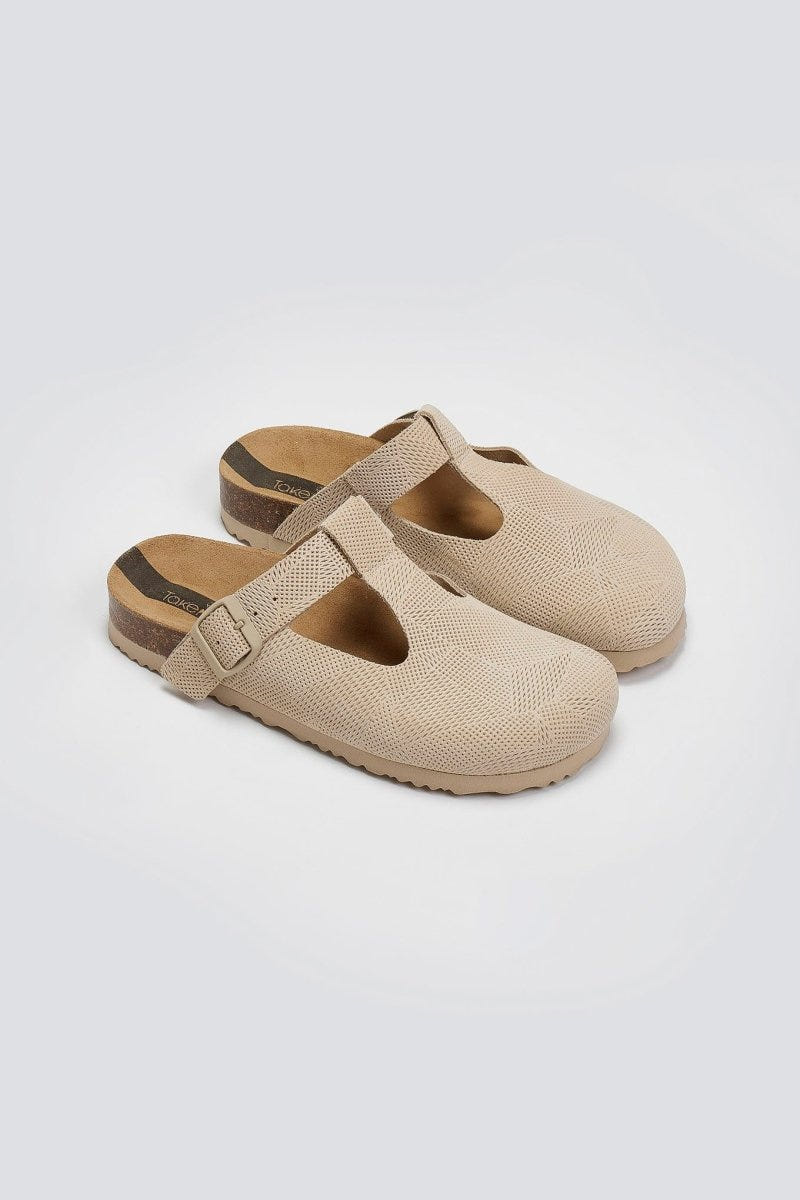 Pair of beige woven T-strap clogs with cork footbeds, angled view on a light background