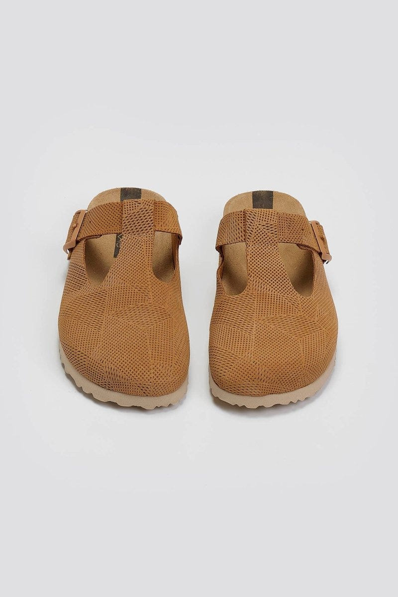Pair of tan suede T-strap clogs with cut-out vamp and buckle, overhead view on a light grey background