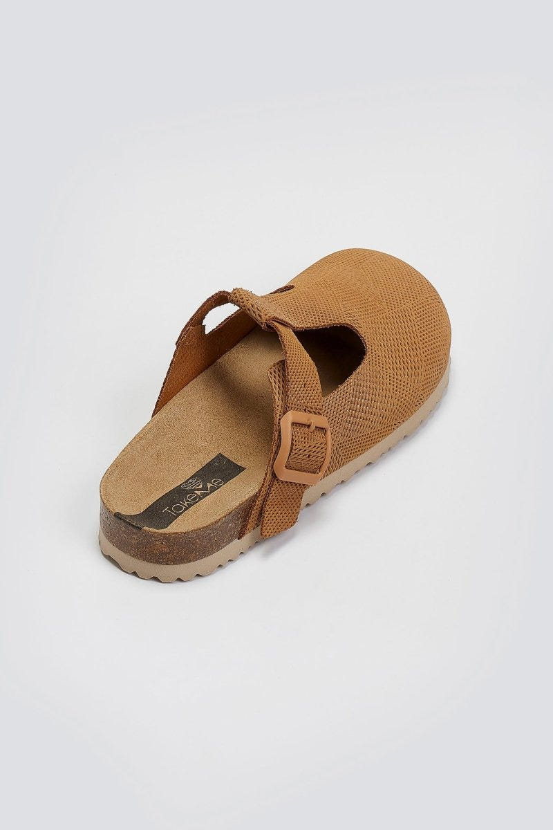 Tan suede T-strap clog with cut-out vamp and buckle, overhead angled view on a light grey background