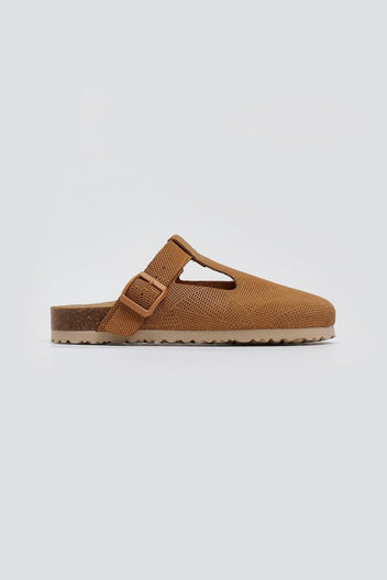 Tan suede T-strap clog with cut-out vamp and buckle, side view on a light grey background