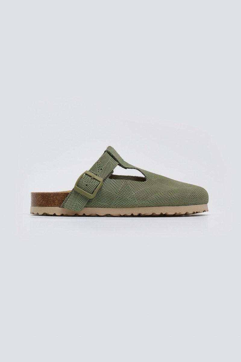 Sage green suede T-strap clog with cut-out vamp and buckle, side view on a light grey background