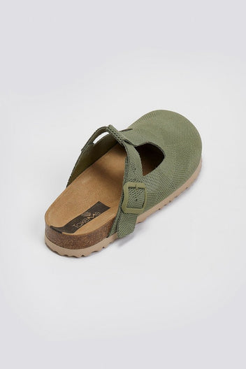 Sage green suede T-strap clog with cut-out vamp and buckle, angled overhead view on a light grey background