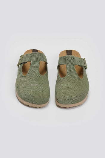 Pair of sage green suede T-strap clogs with cut-out vamp and buckle, overhead view on a light grey background