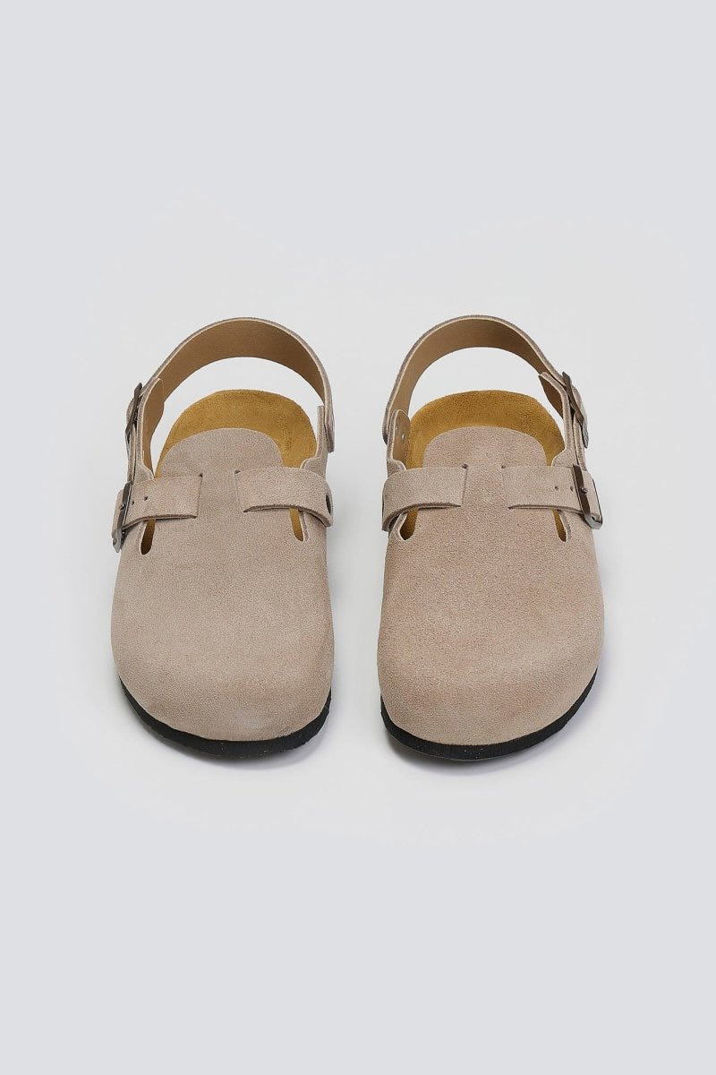 Pair of taupe suede clogs with ankle strap and buckle, overhead view on a light grey background