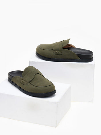 Olive green suede loafer-style mule with black rubber sole, angled view on a white display block