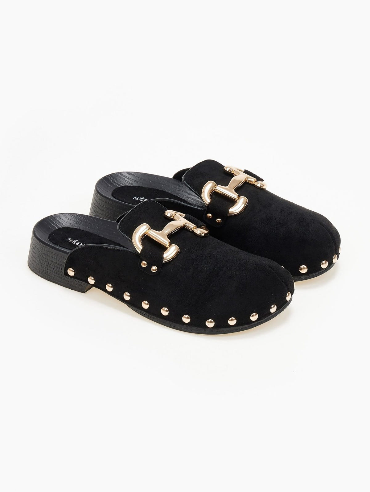 Pair of black suede clogs with gold horsebit buckle and gold stud trim on a cork footbed, angled view on a white background