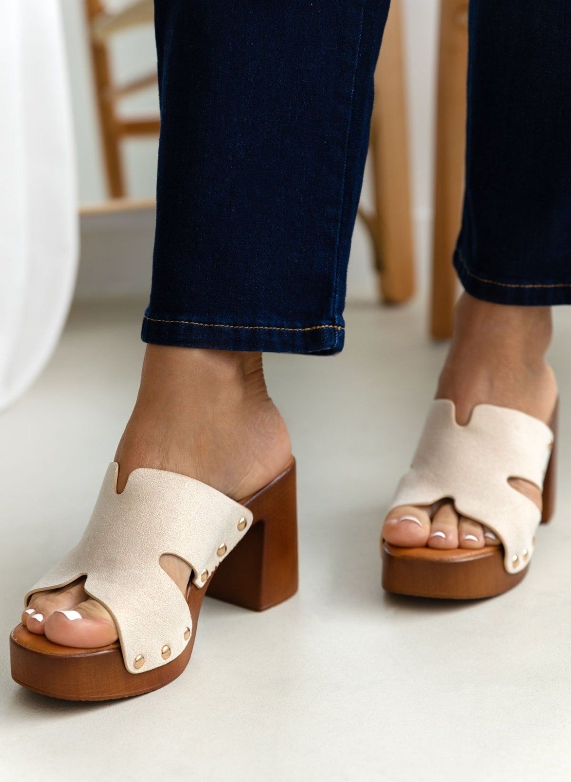 Model feet in cream suede block heel slides with tan platform, worn with dark jeans, angled view on a light backdrop