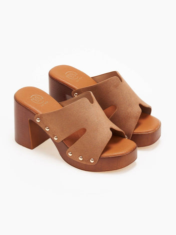 Pair of tan suede block heel slides with cut-out straps, gold studs and wooden-look platform, angled view on a white background